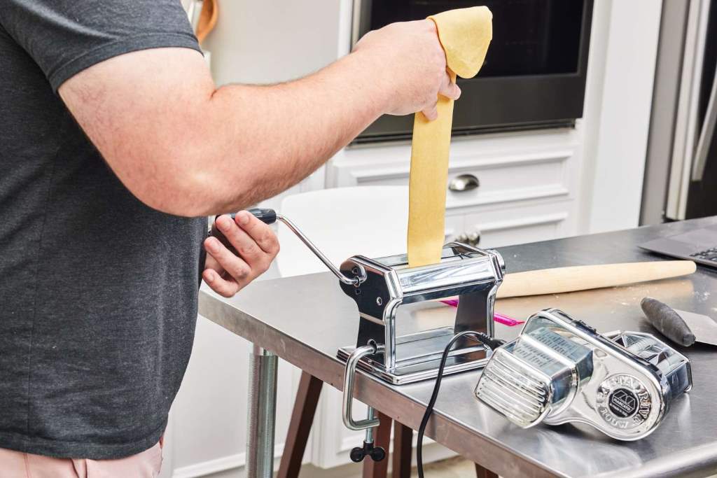 Family using Marcato Atlas pasta machine complete set with Pastadrive motor rolling bright yellow egg dough