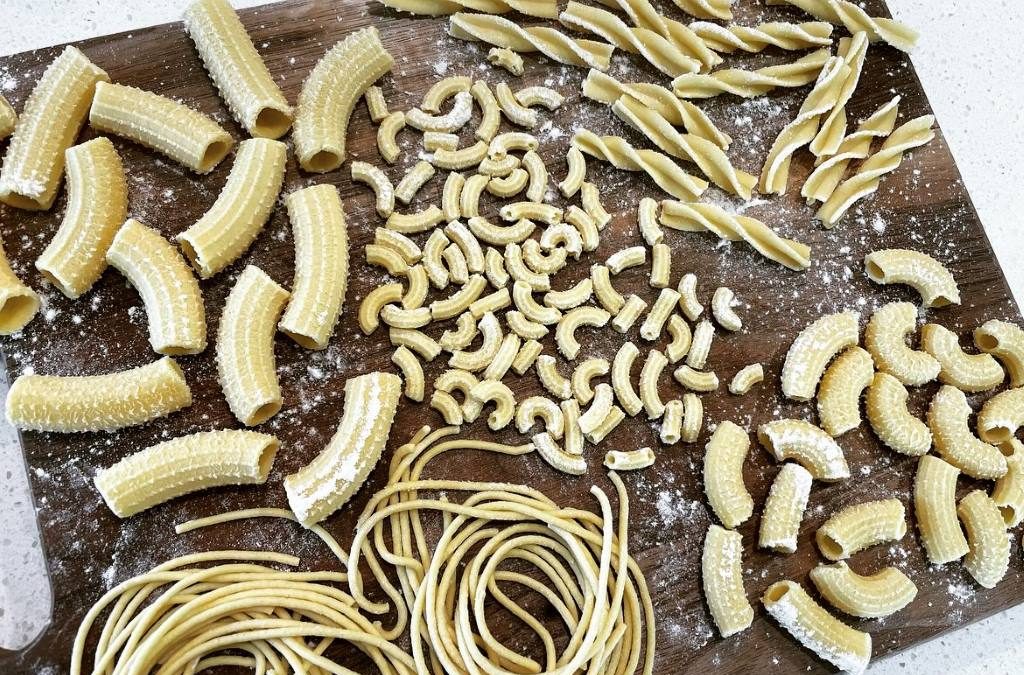 Italy pasta extruder creating perfect rigatoni strands dusted with semolina