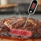 Digital meat thermometer inserted into thick steak showing temperature reading for proper doneness checking