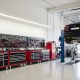 Clean and organized auto repair garage with a vehicle on a two-post lift and tool chests along the wall