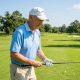 A senior golfer holding a club with a large midsize golf grip on a sunny green fairway