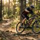 Cyclist riding a new full suspension mountain bike on a sunny dirt trail.
