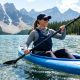Woman hikes sunny mountain trail wearing light blue UPF sun shirt.
