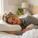 Woman sleeping comfortably on her side using a white orthopedic neck pillow.