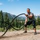 A climber inspecting a sturdy climbing rope anchored on a rugged Colorado mountain cliff.