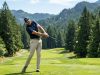 Male golfer hitting a driver off the tee on a tree-lined Washington fairway.