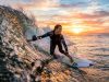 Surfer riding a wave while holding a waterproof action camera at sunset