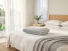 A breathable cooling pillow on a crisp white bed in a bright, sunlit tropical bedroom.