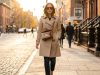 Woman walking outdoors wearing a geometric puzzle crossbody bag with a trench coat.